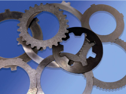 Discos de embrague y engranajes de metal sobre un fondo azul, probablemente componentes de automoción.