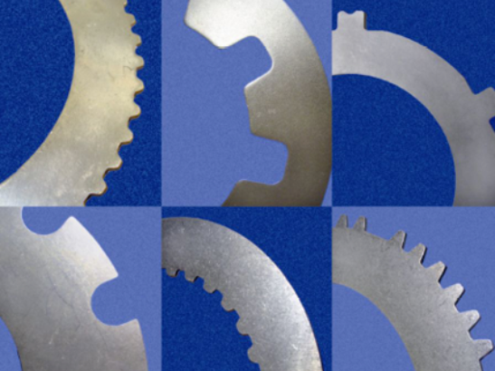 Seis discos de embrague de metal con distintos dientes y muescas, sobre un fondo azul.