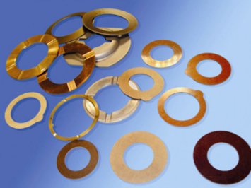 Varias arandelas de metal en diferentes tamaños, formas y colores, mostradas sobre un fondo azul.