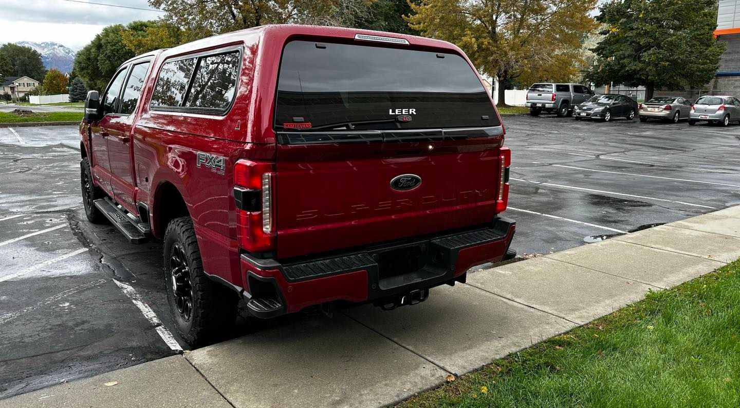 A red truck is parked in a parking lot next to a sidewalk.