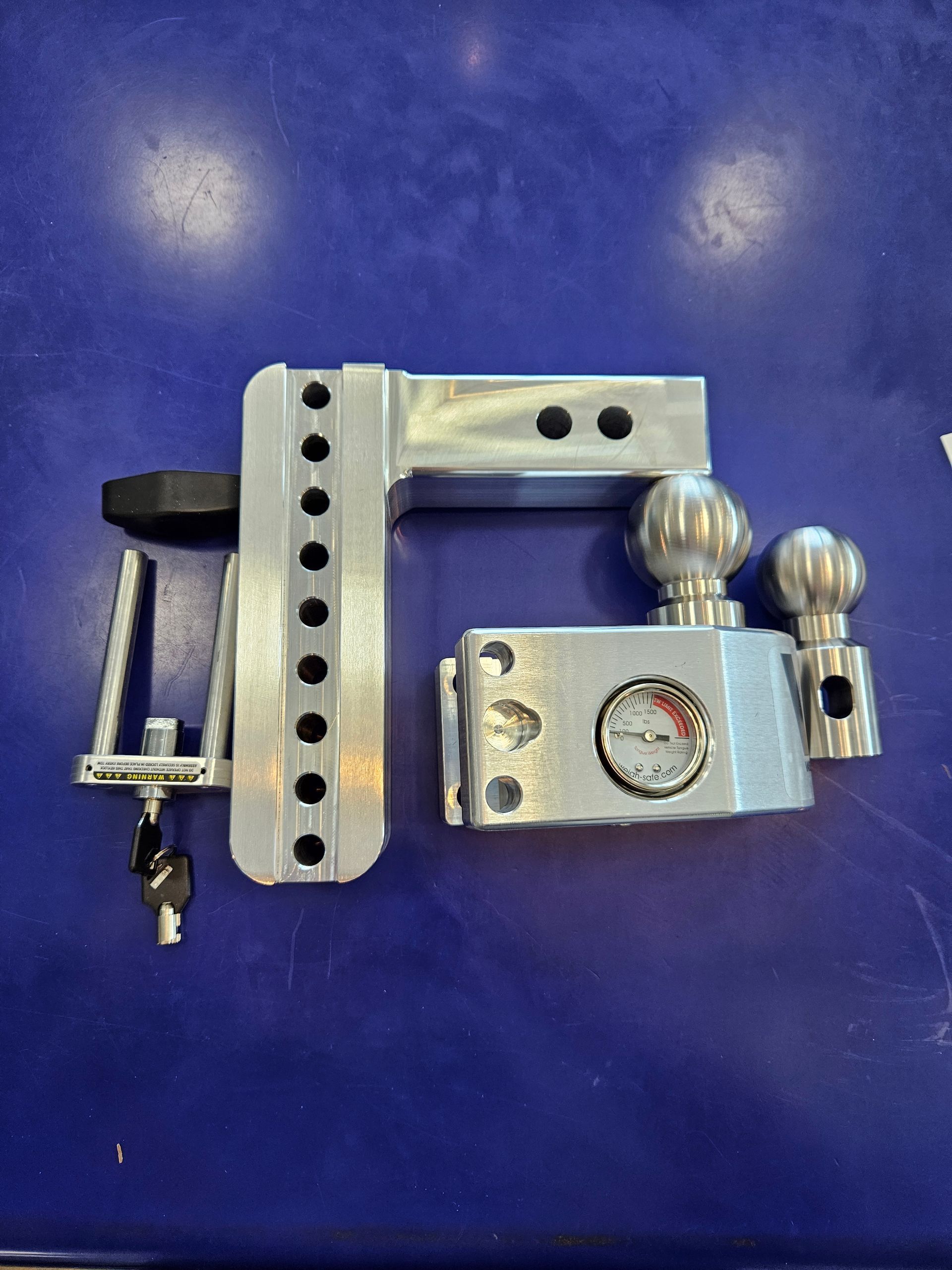 A metal object with a clock on it is sitting on a blue table.