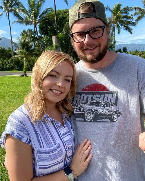 A man and a woman are posing for a picture in a park.