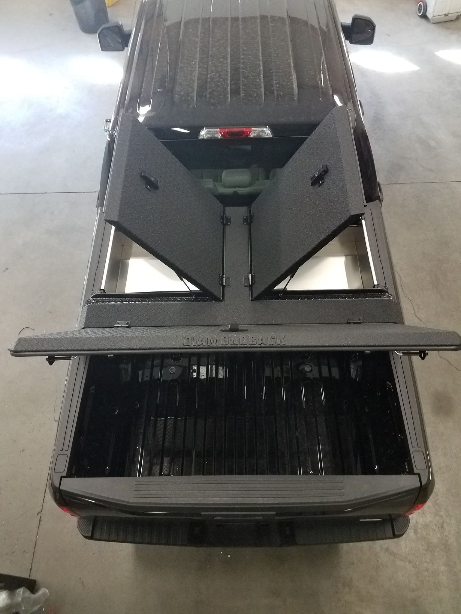 The back of a black truck with the bed open