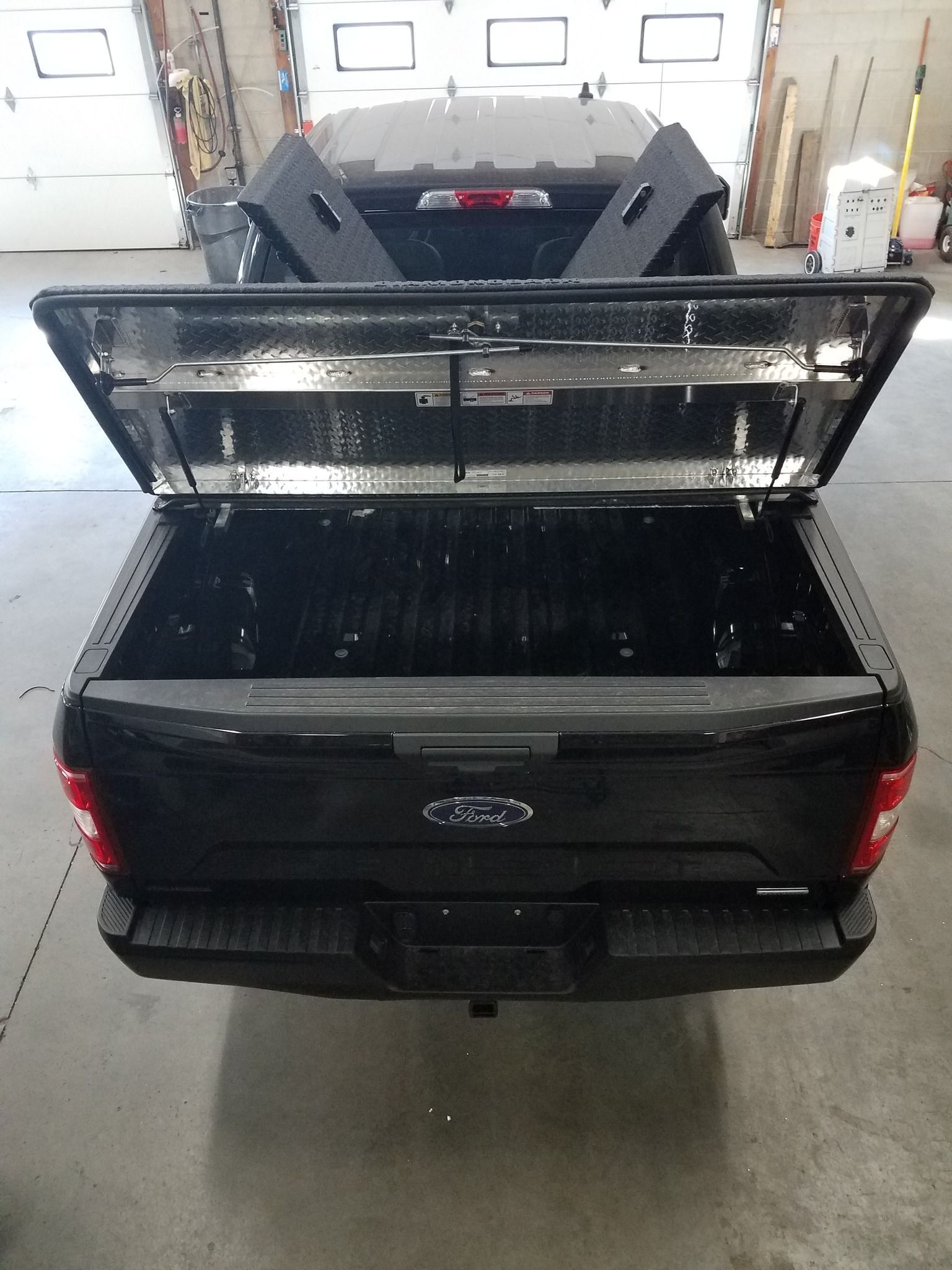 A black ford truck with the bed cover open