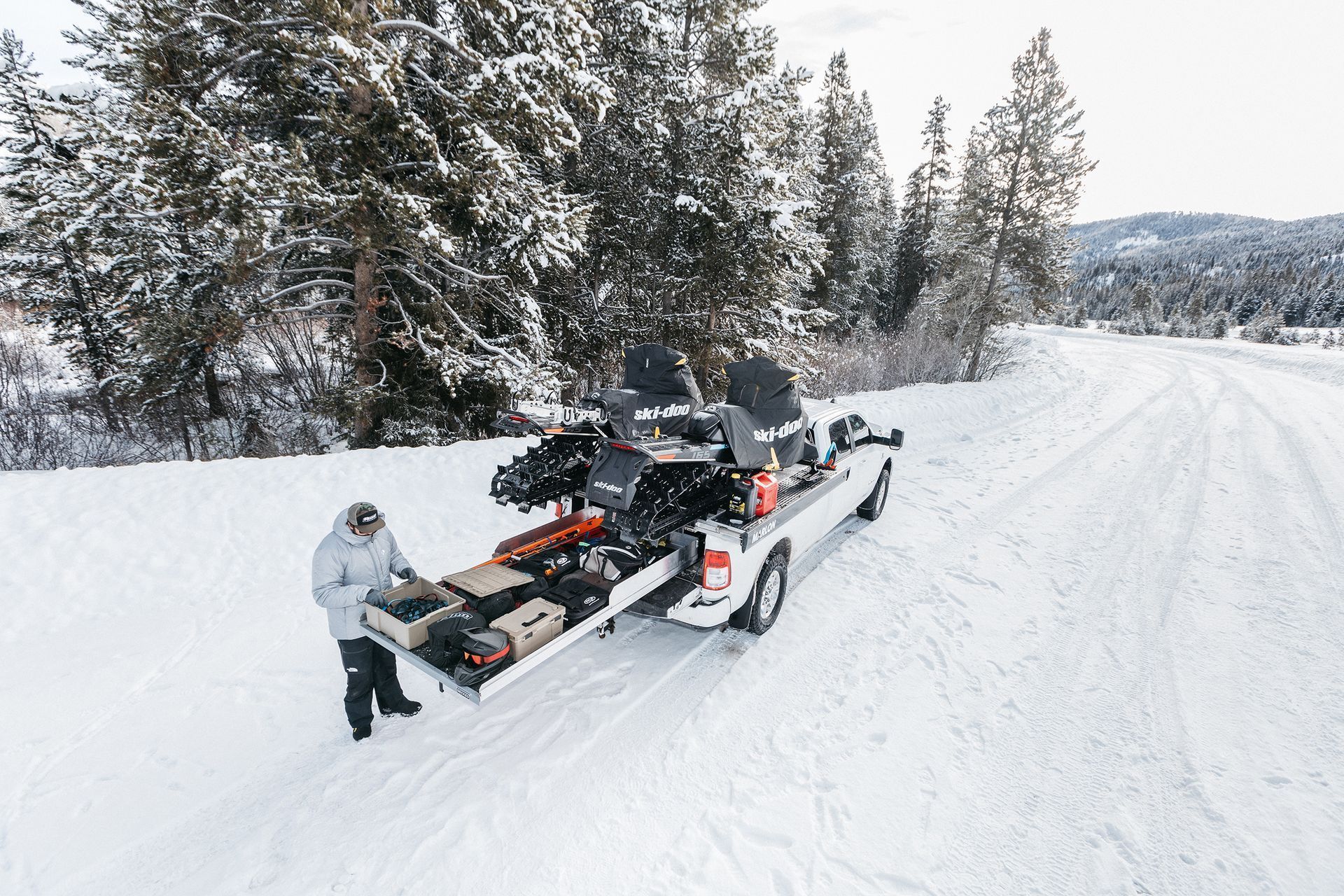 A man is pulling a snowmobile out of the back of a truck.