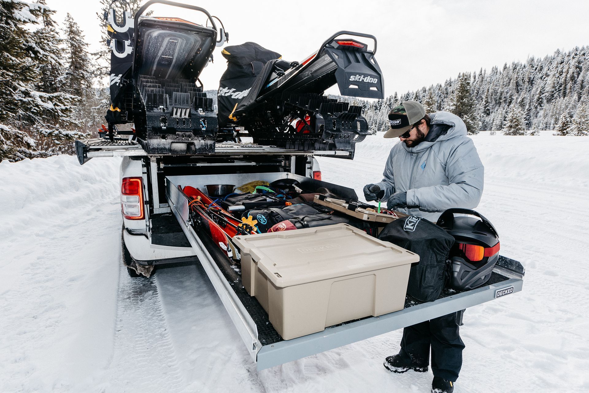 A man is loading a snowmobile into the back of a truck.