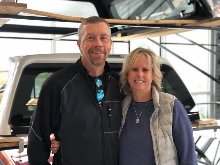 A man and a woman are posing for a picture in front of a truck.