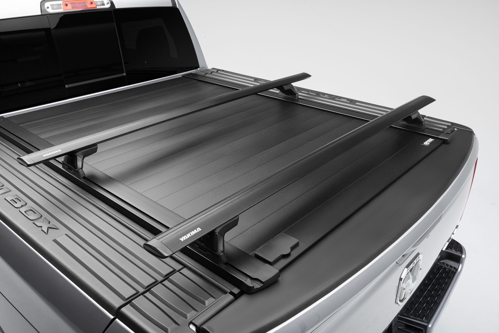 A silver truck with a black bed cover on it