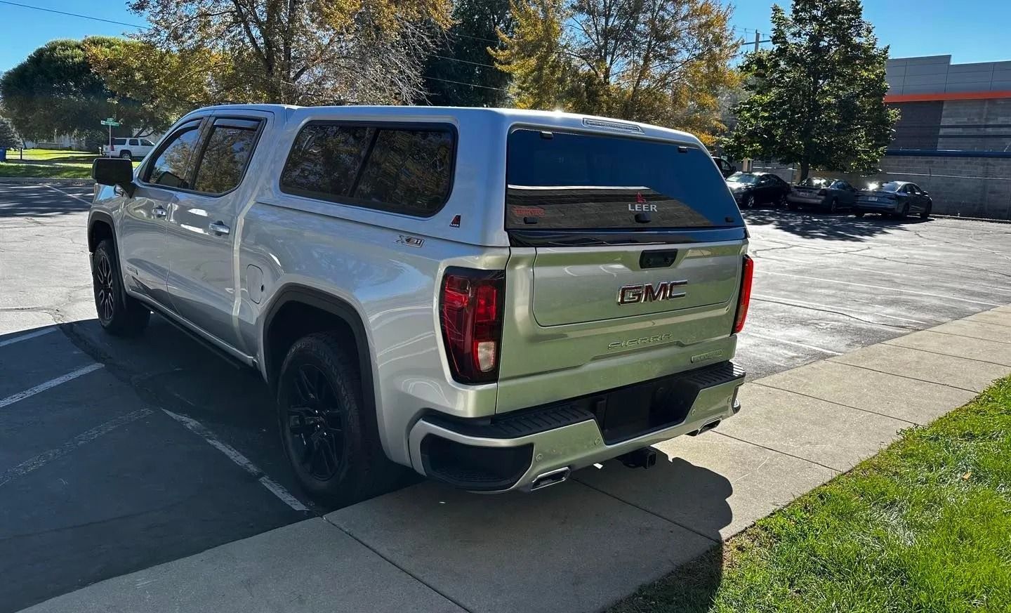 A white truck with a canopy is parked on the side of the road.
