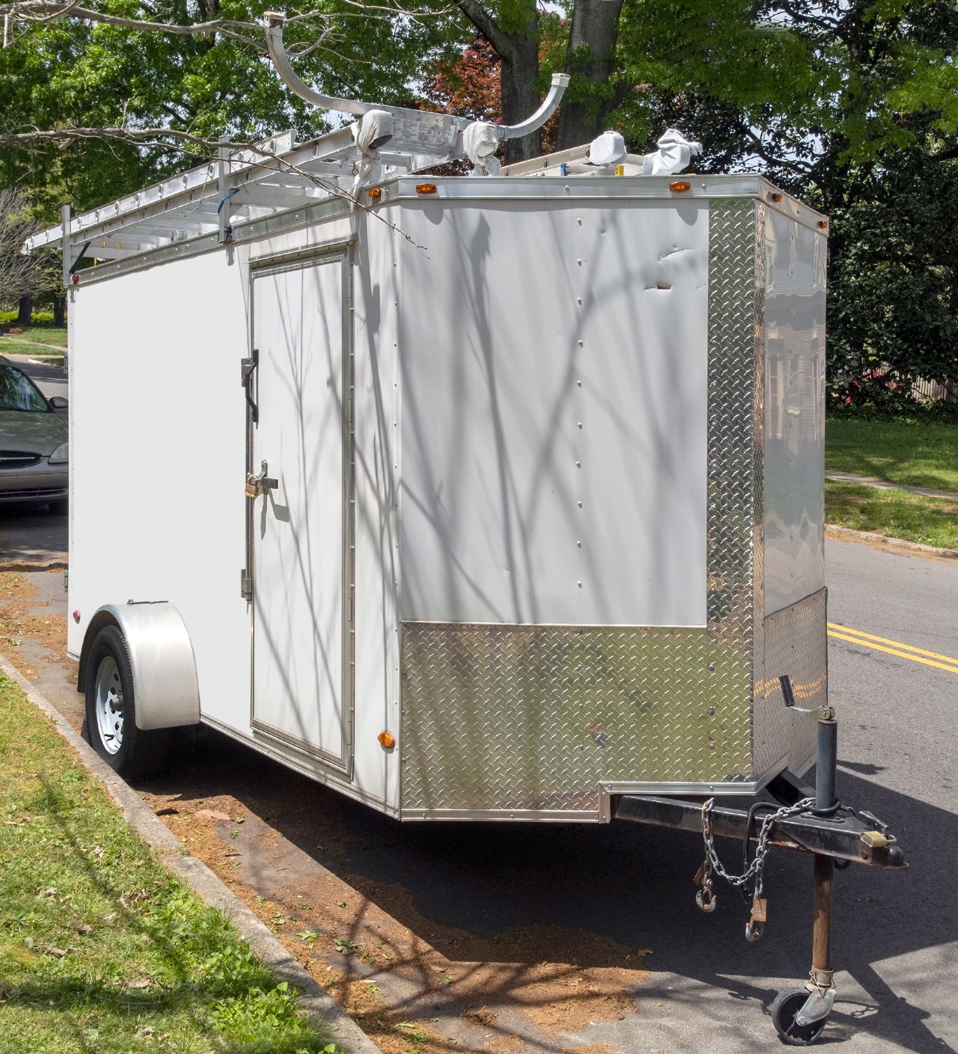 A white trailer is parked on the side of the road