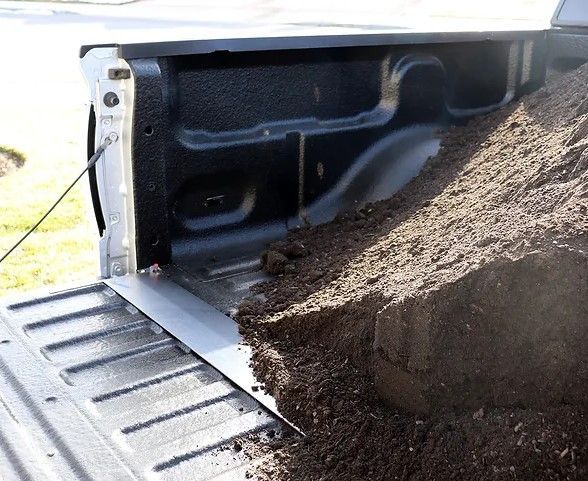 A truck bed with a pile of dirt in it