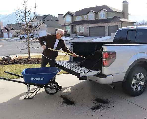 A man is loading a wheelbarrow into the back of a truck