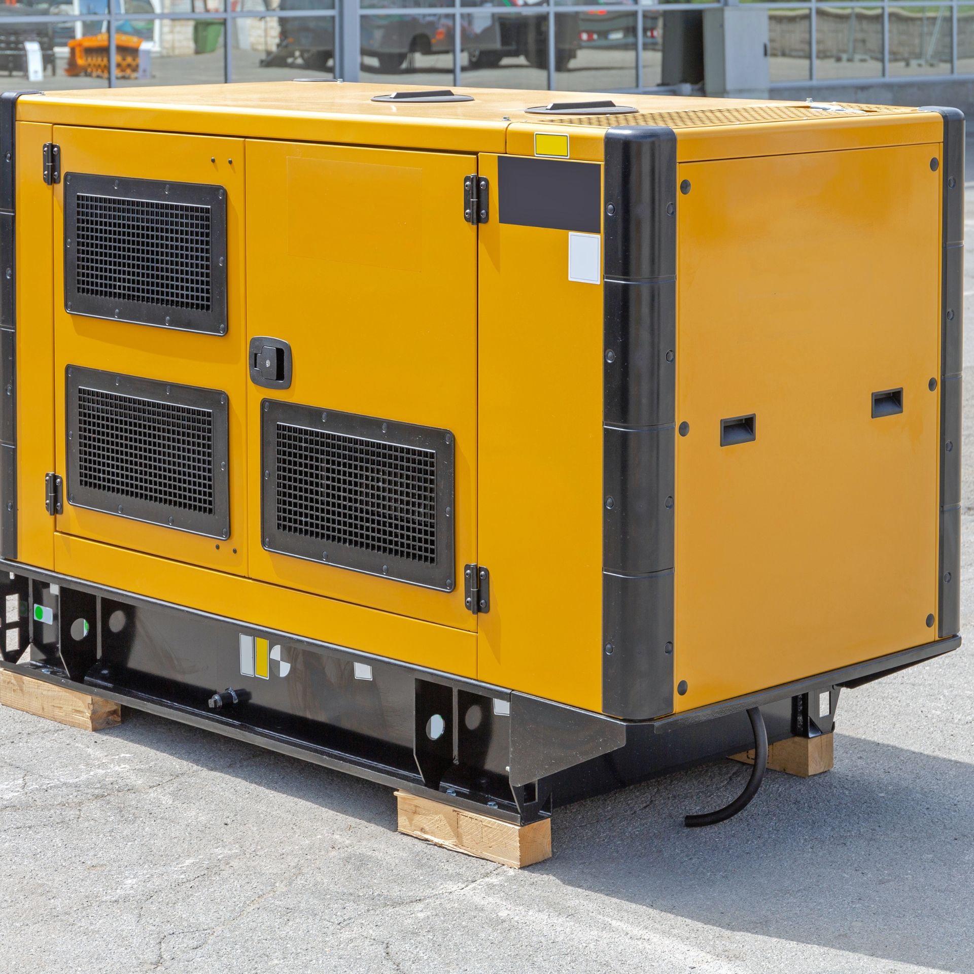 MJS Electrical Services - Yellow industrial generator on a wooden pallet outdoors.