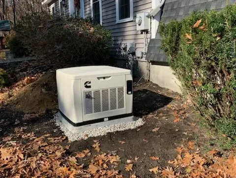 A generator is sitting in the dirt in front of a house.