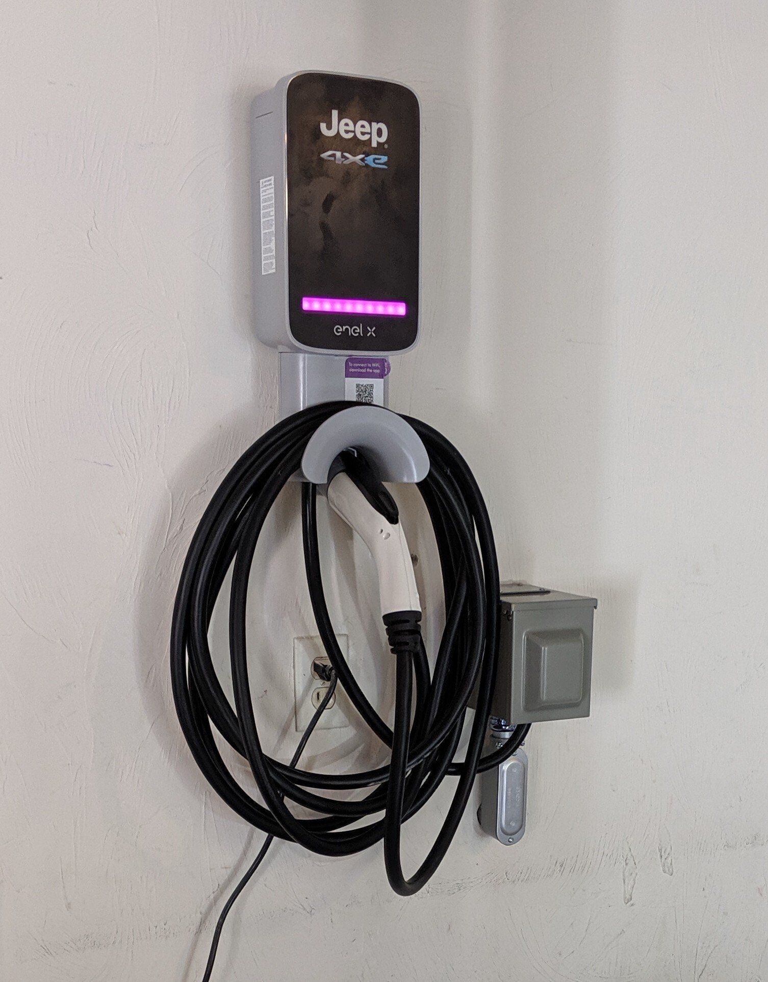 A jeep electric car charger is hanging on a wall.