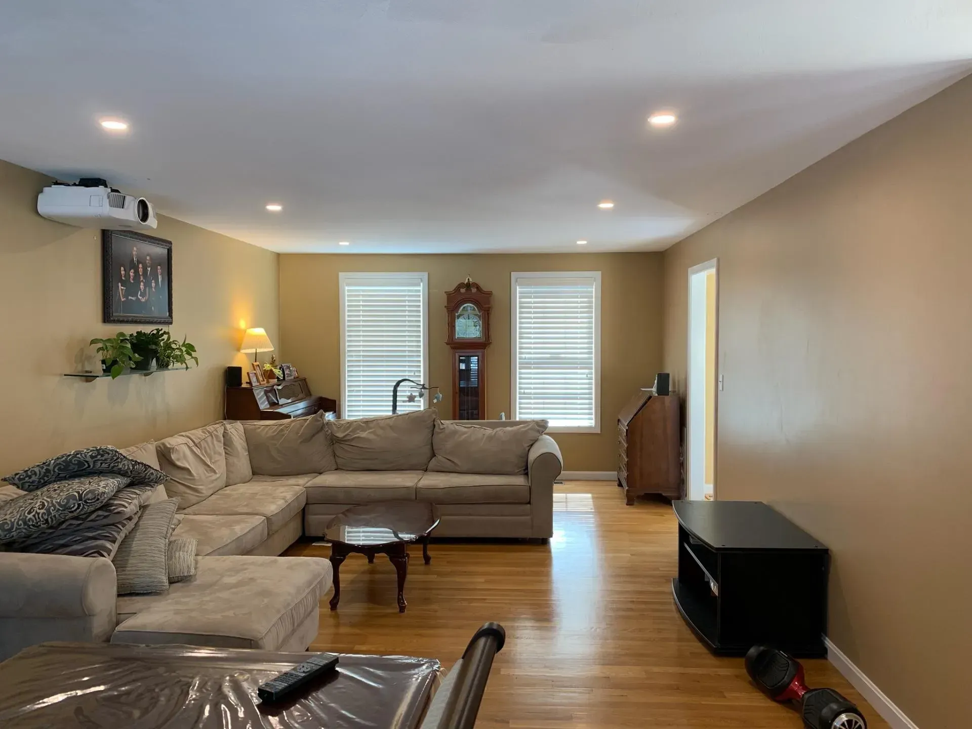 A living room with a couch , table , vacuum cleaner and clock.