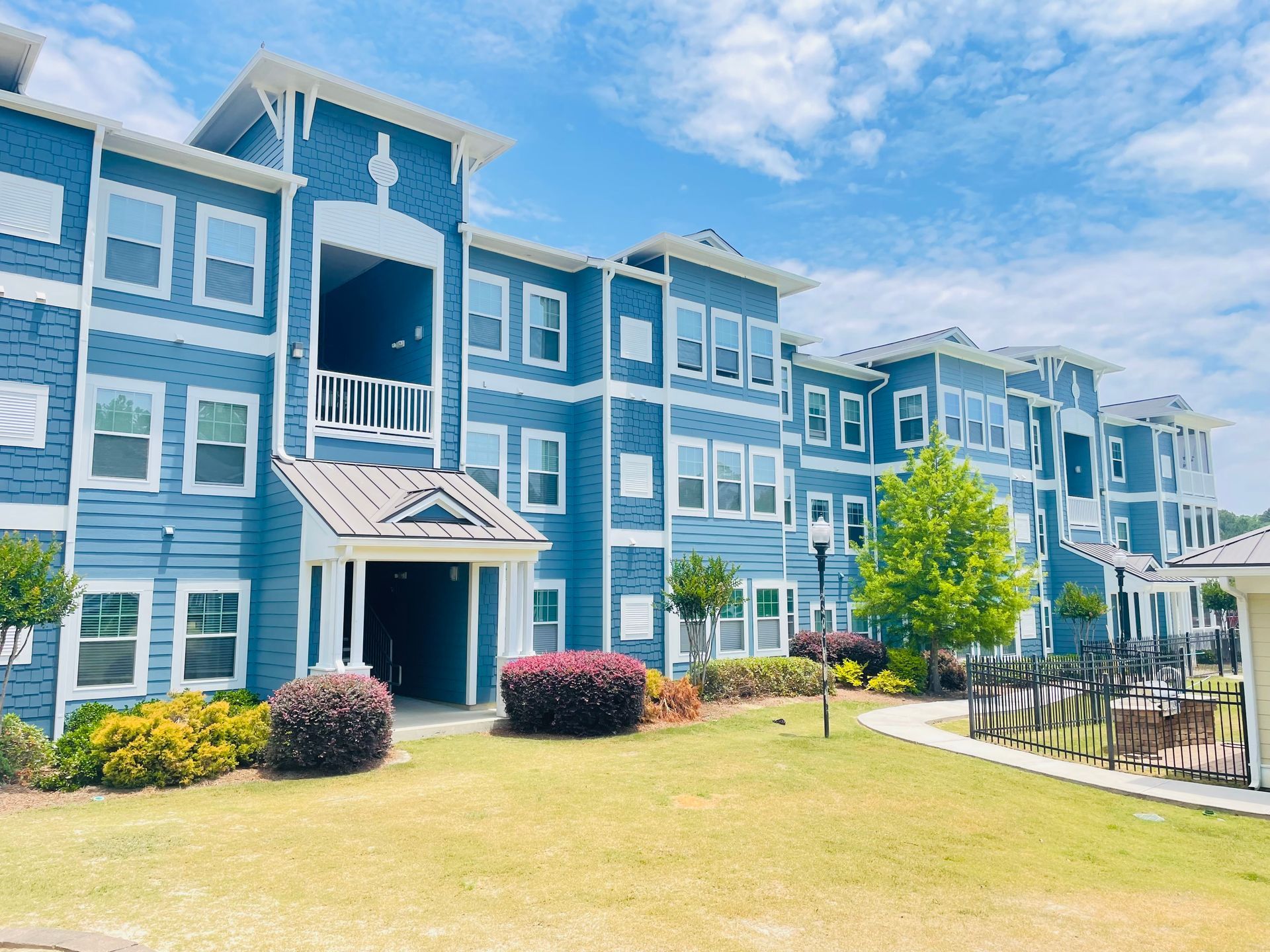 A large blue apartment building with a lot of windows at Thomaston Crossing.