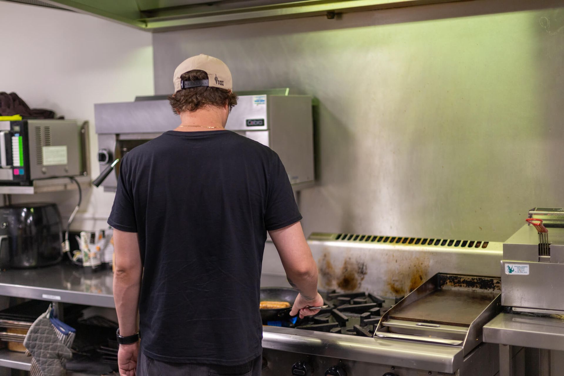 A man is standing in a kitchen cooking on a stove.