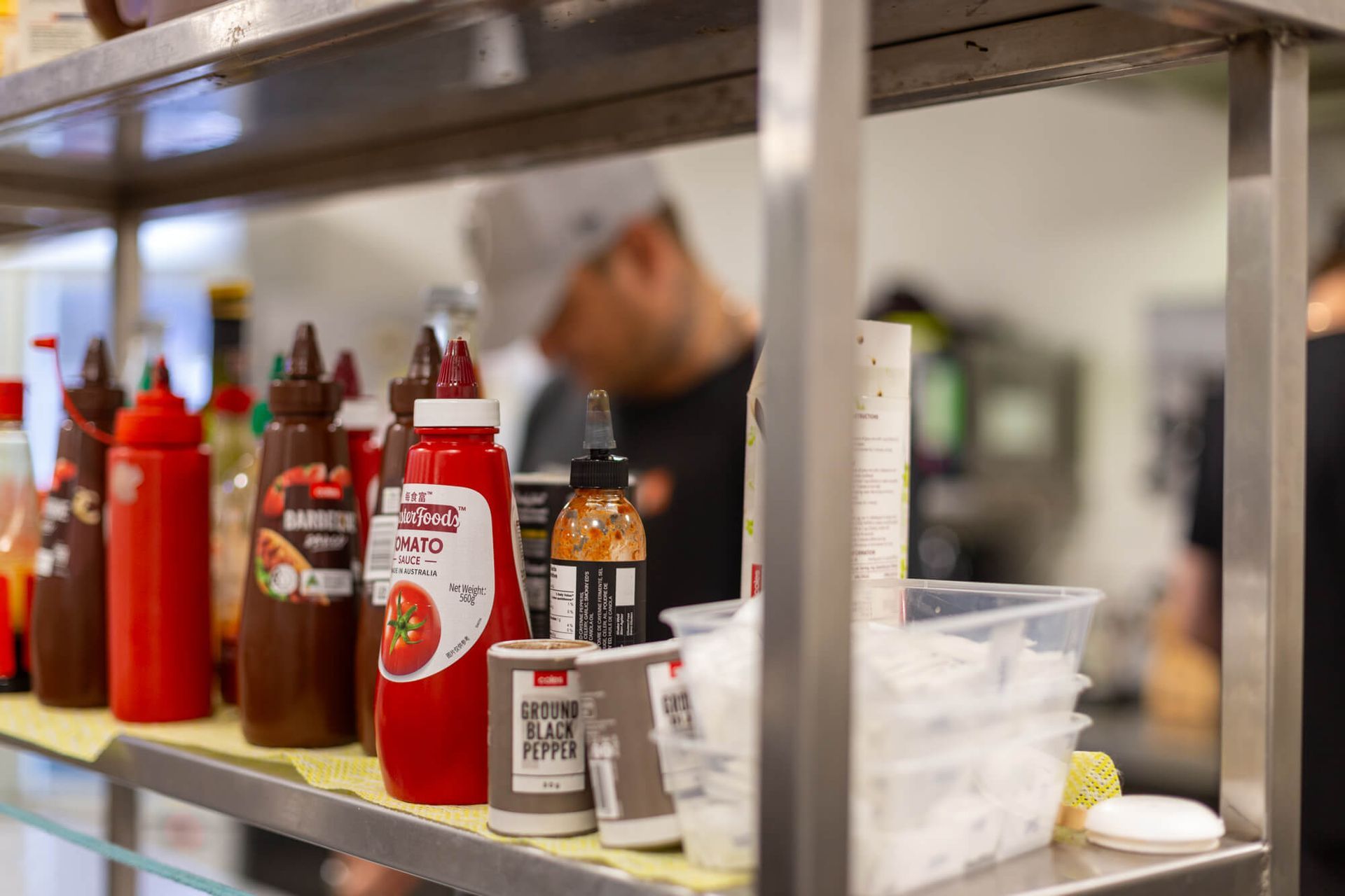 A shelf filled with bottles of sauces and condiments in a kitchen.