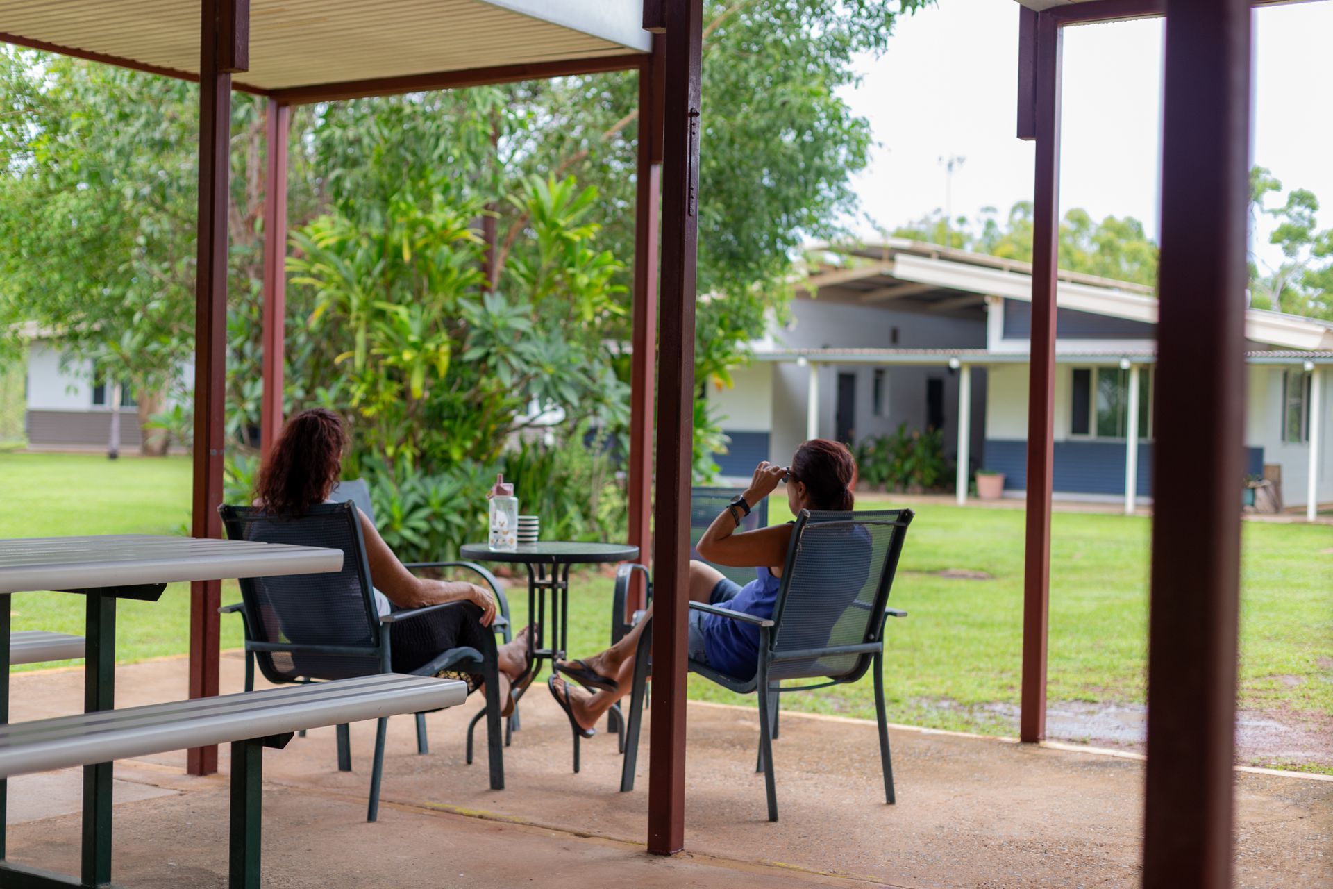 Two people are sitting at a picnic table under a canopy.