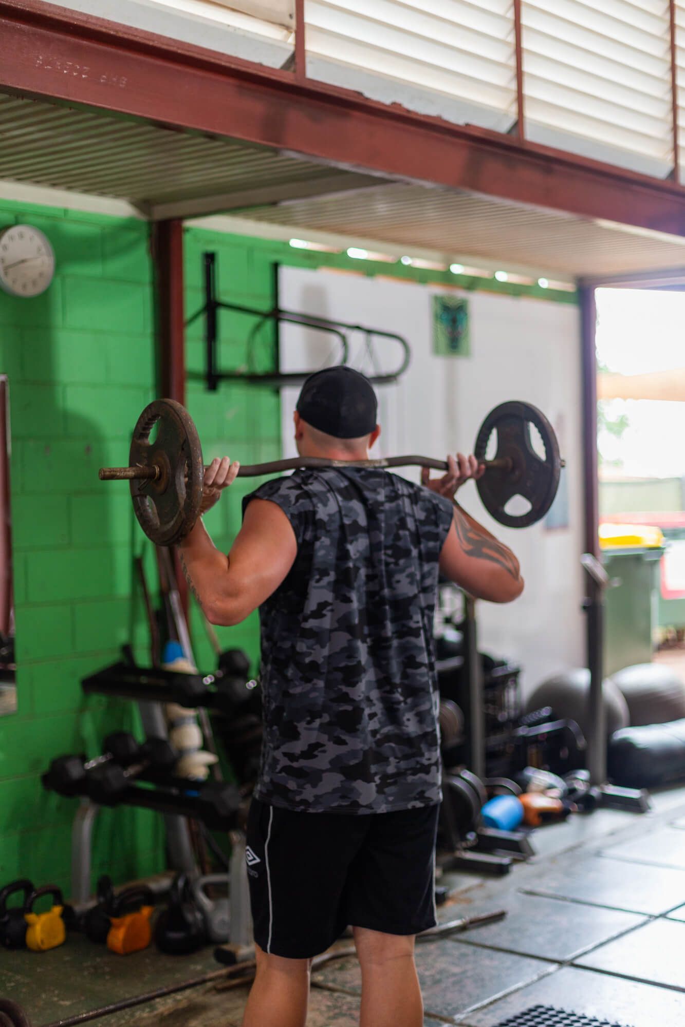 A man is squatting with a barbell in a gym.