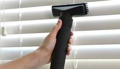 Hand Using Vacuum To Clean Blinds — Brisbane, QLD — Sun Stop Blinds