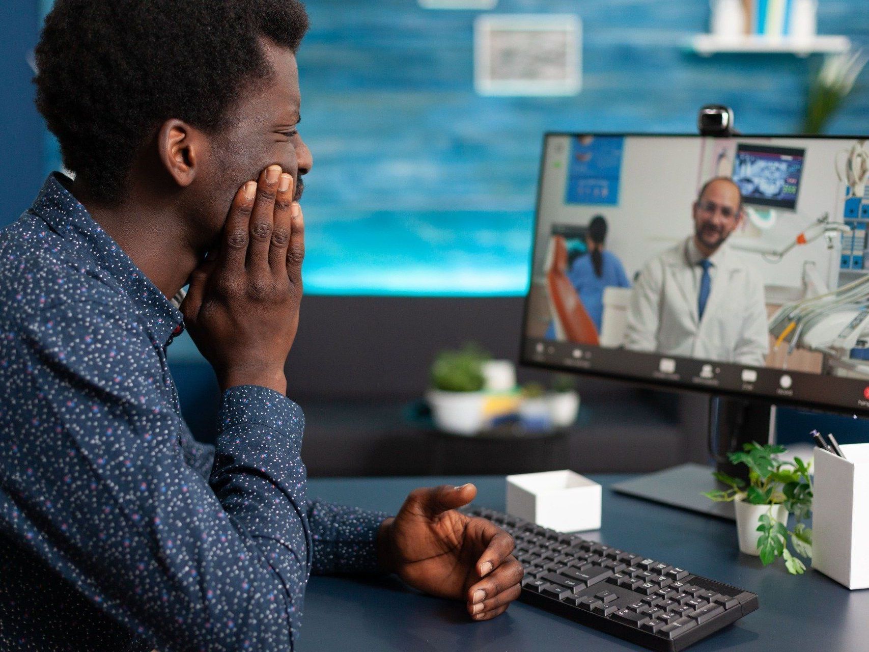 An image of a black man with tooth pain on a virtual call with a dentist