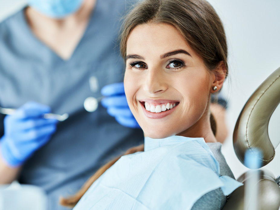 A photo of a young woman in a dental chair smiling at the camera