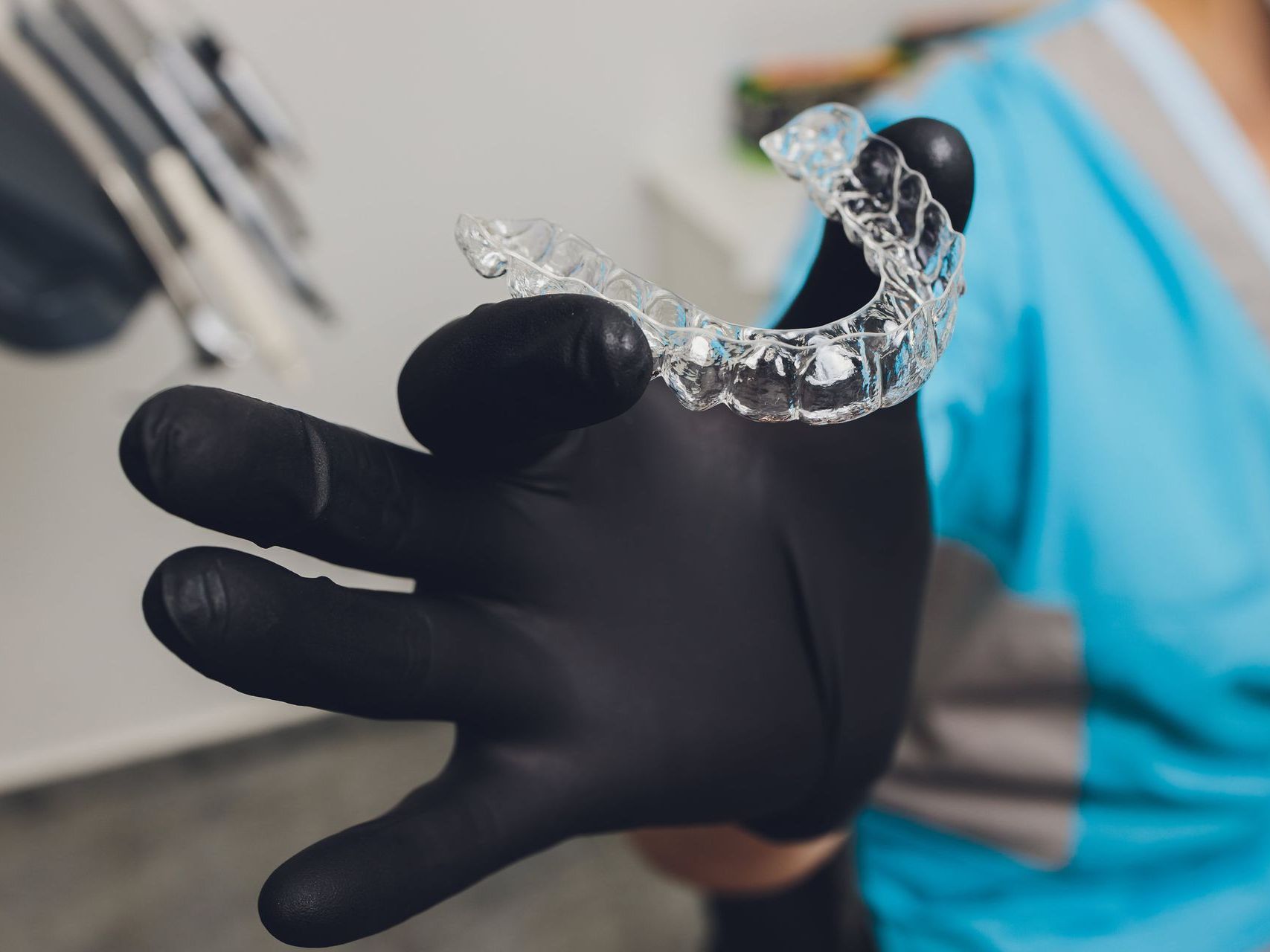 An image of a dental assistant holding a clear aligner tray