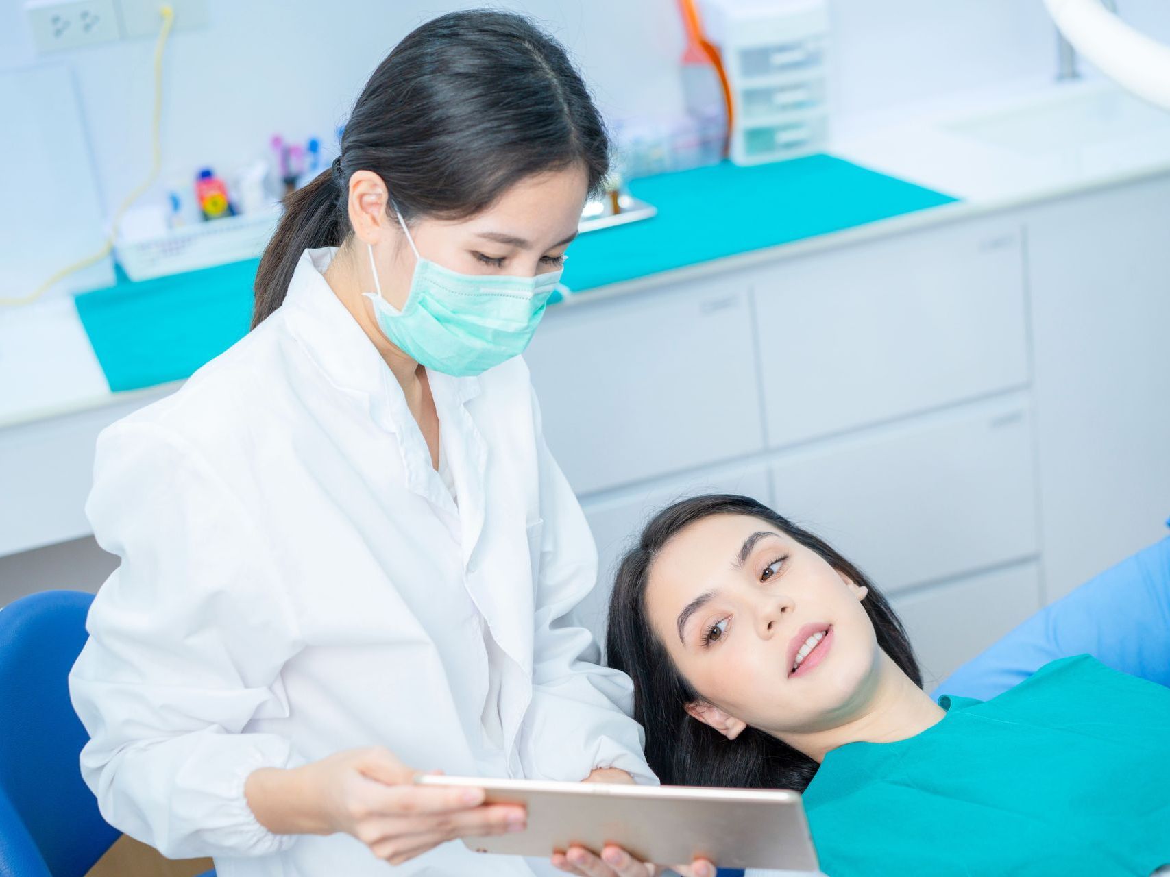 An image of a female dentist showing a tablet to a female patient