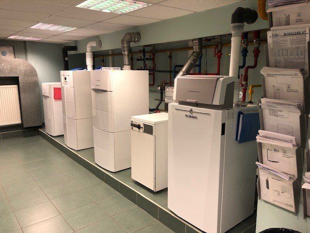 Une rangée de chaudières blanches est alignée dans une pièce