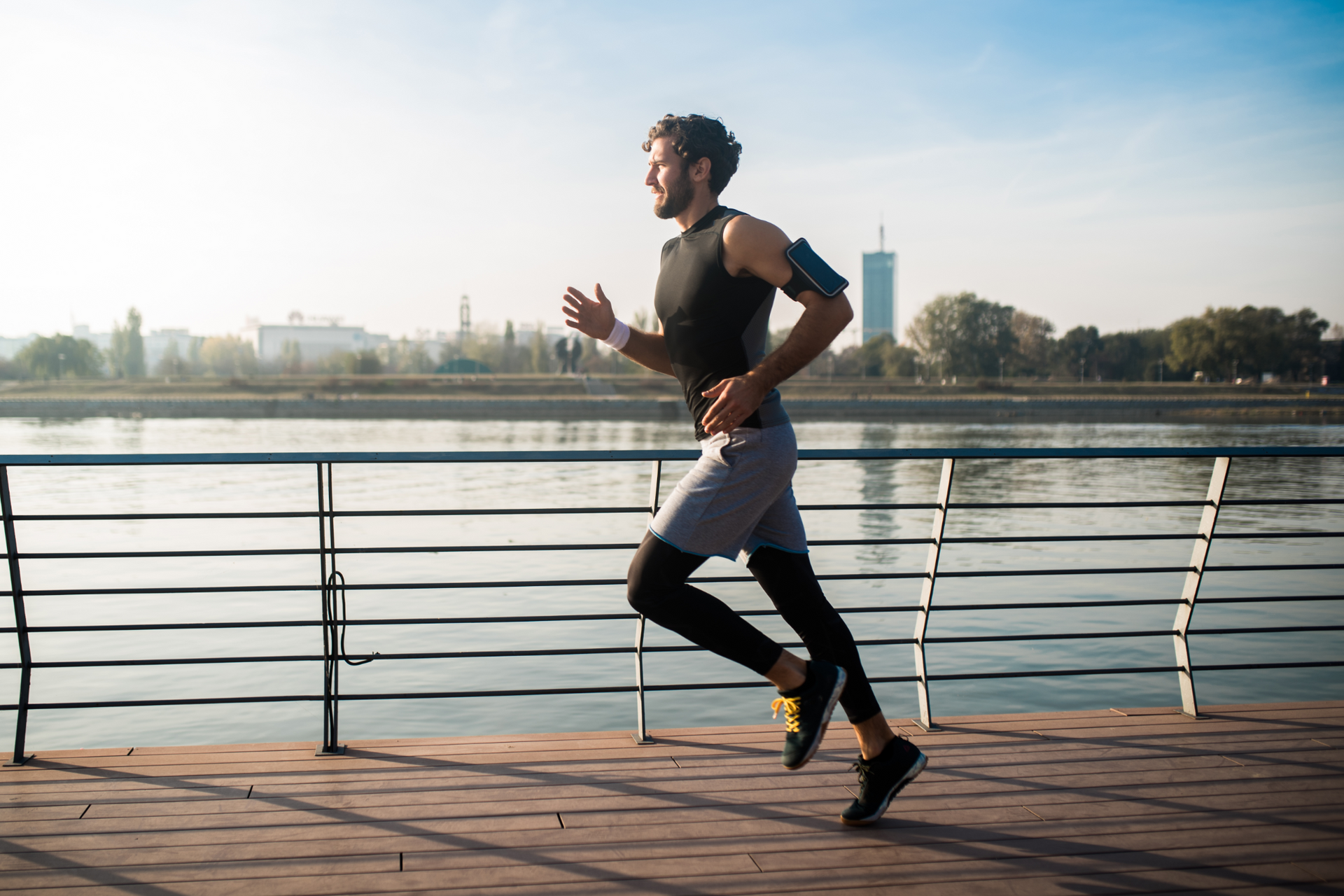 A man is running on a pier next to a body of water.