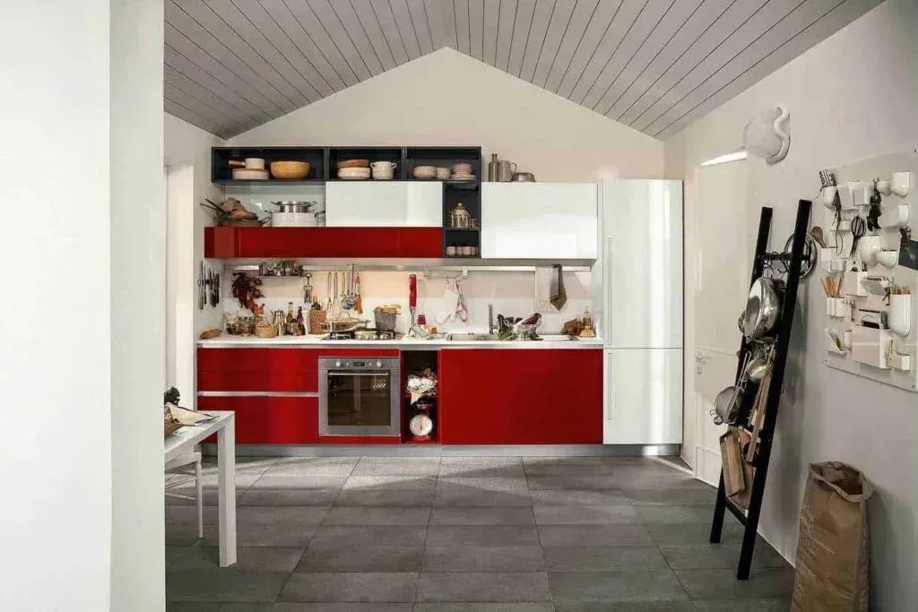 Red and white modern kitchen with gray tile floor, black ladder and a bag.