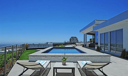 There is a large swimming pool in the backyard of a house.