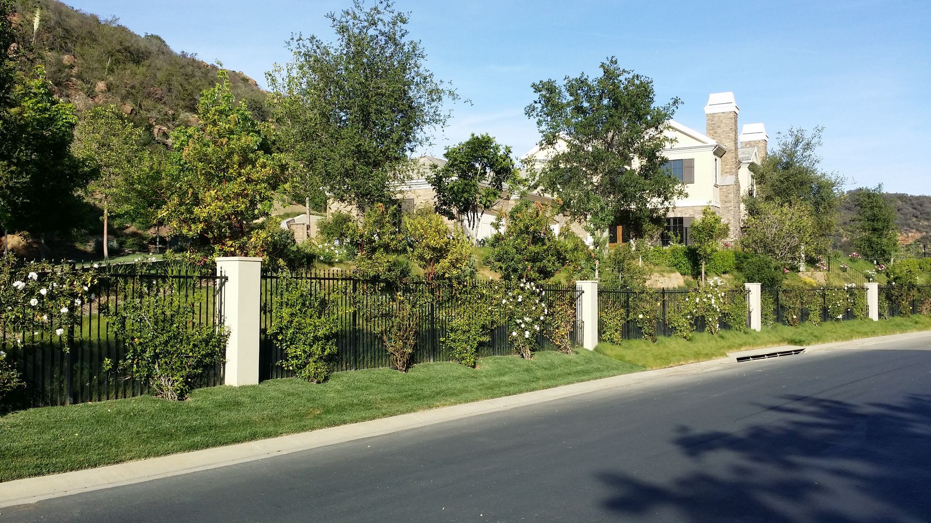 A large house is surrounded by a fence and trees