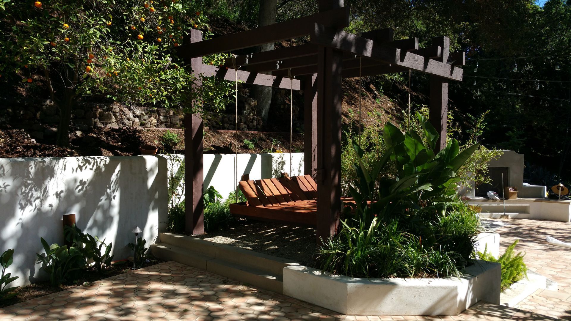A pergola with a swing underneath it in a garden