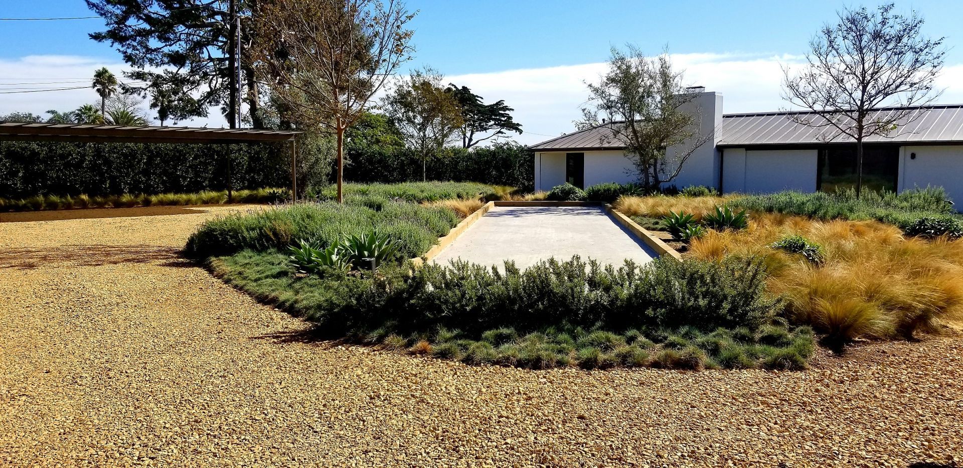 A gravel driveway leading to a house with trees in the background.