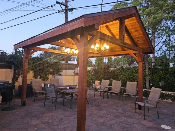 A wooden gazebo with tables and chairs underneath it