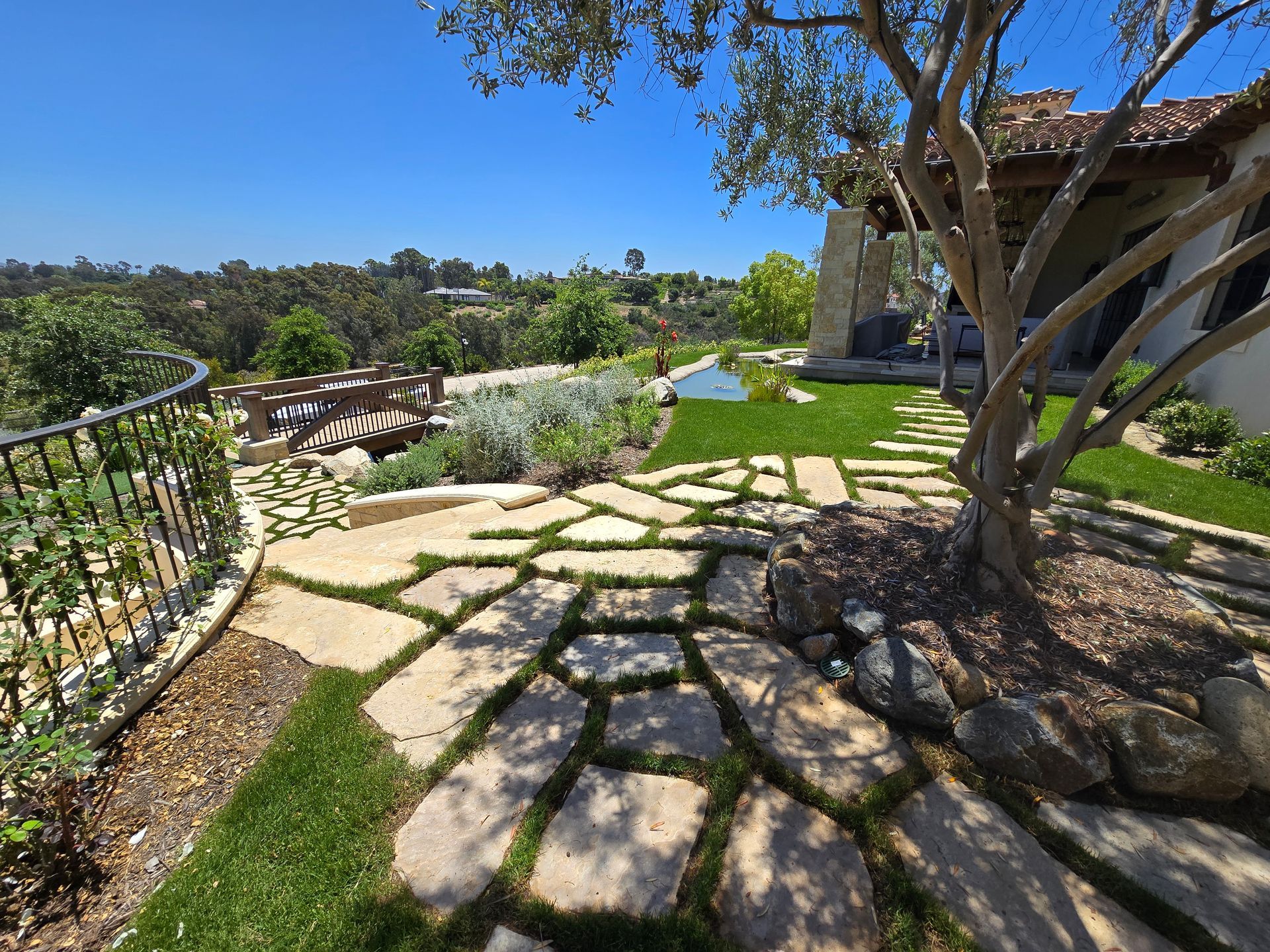 A stone walkway leading to a house with a tree in the middle