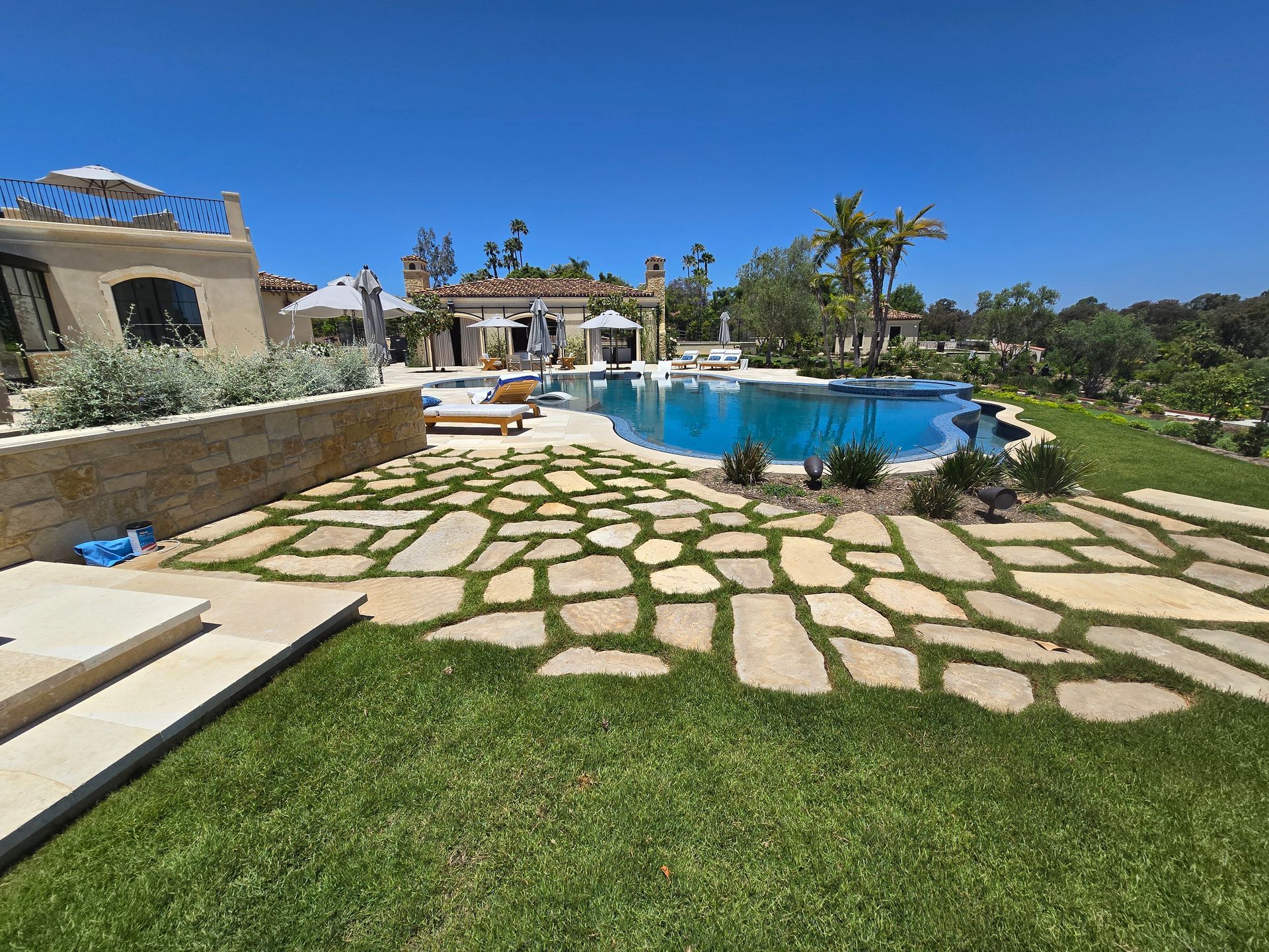 There is a large swimming pool in the backyard of a house.