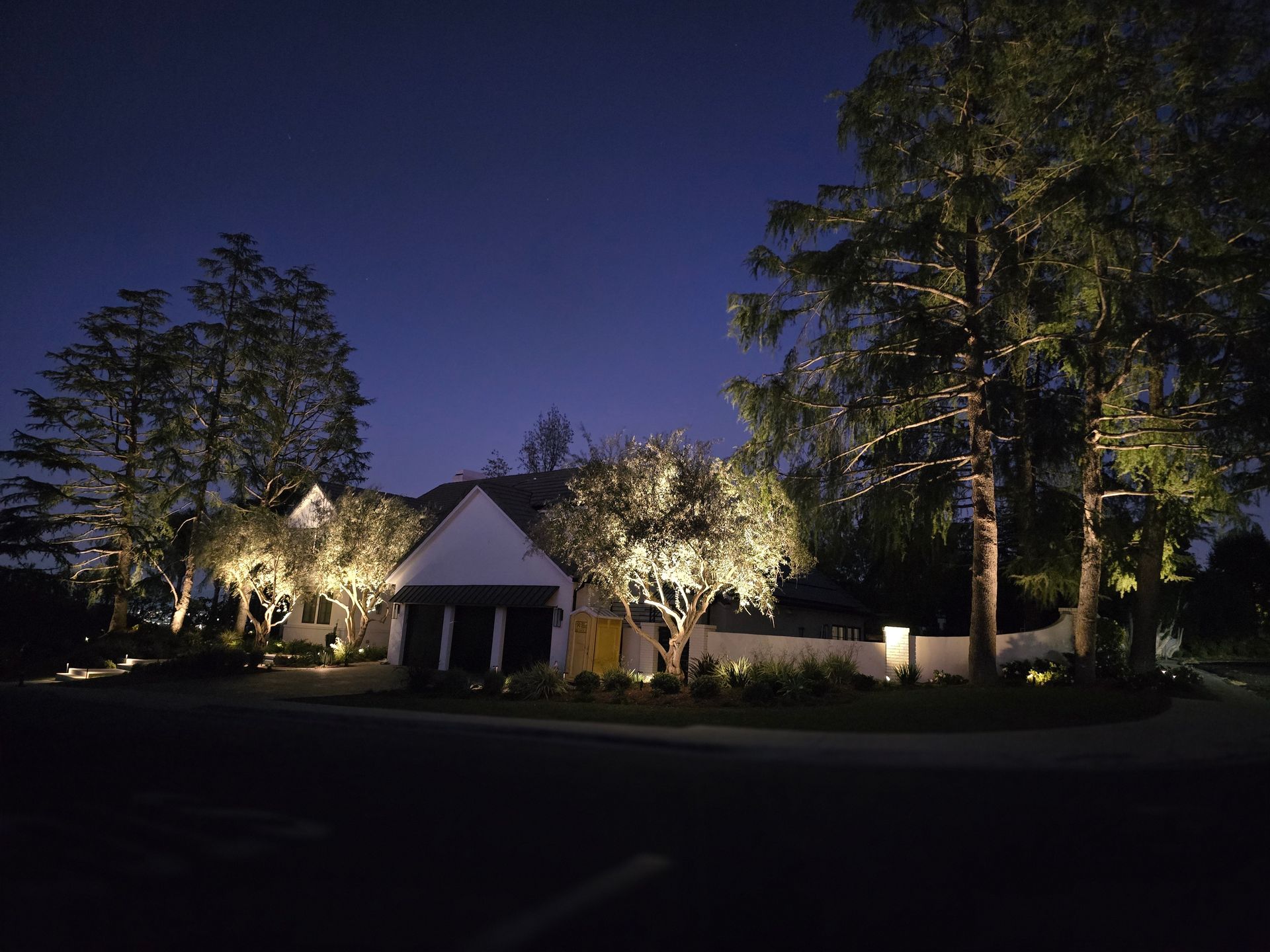 A house is lit up at night with trees in front of it