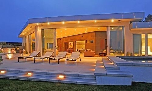 A large house with a lot of windows and chairs on the patio