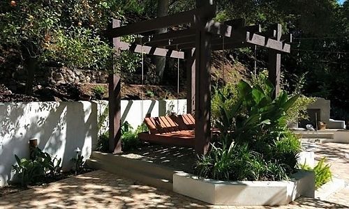 A pergola with chairs underneath it in a garden