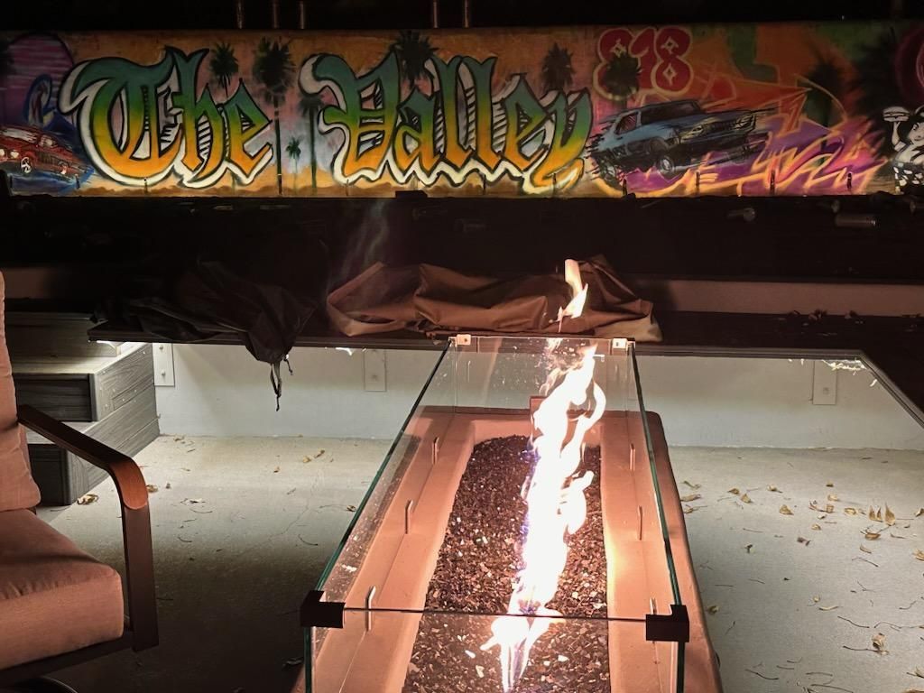 A fire pit in front of a graffiti wall that says the falls