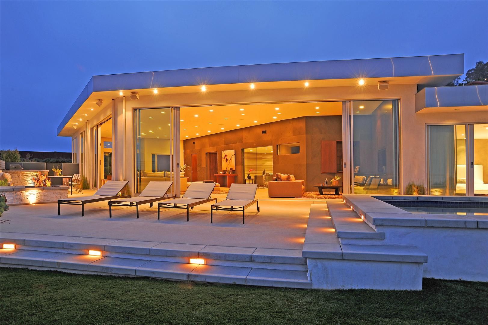 A large house with a lot of windows and chairs on the patio