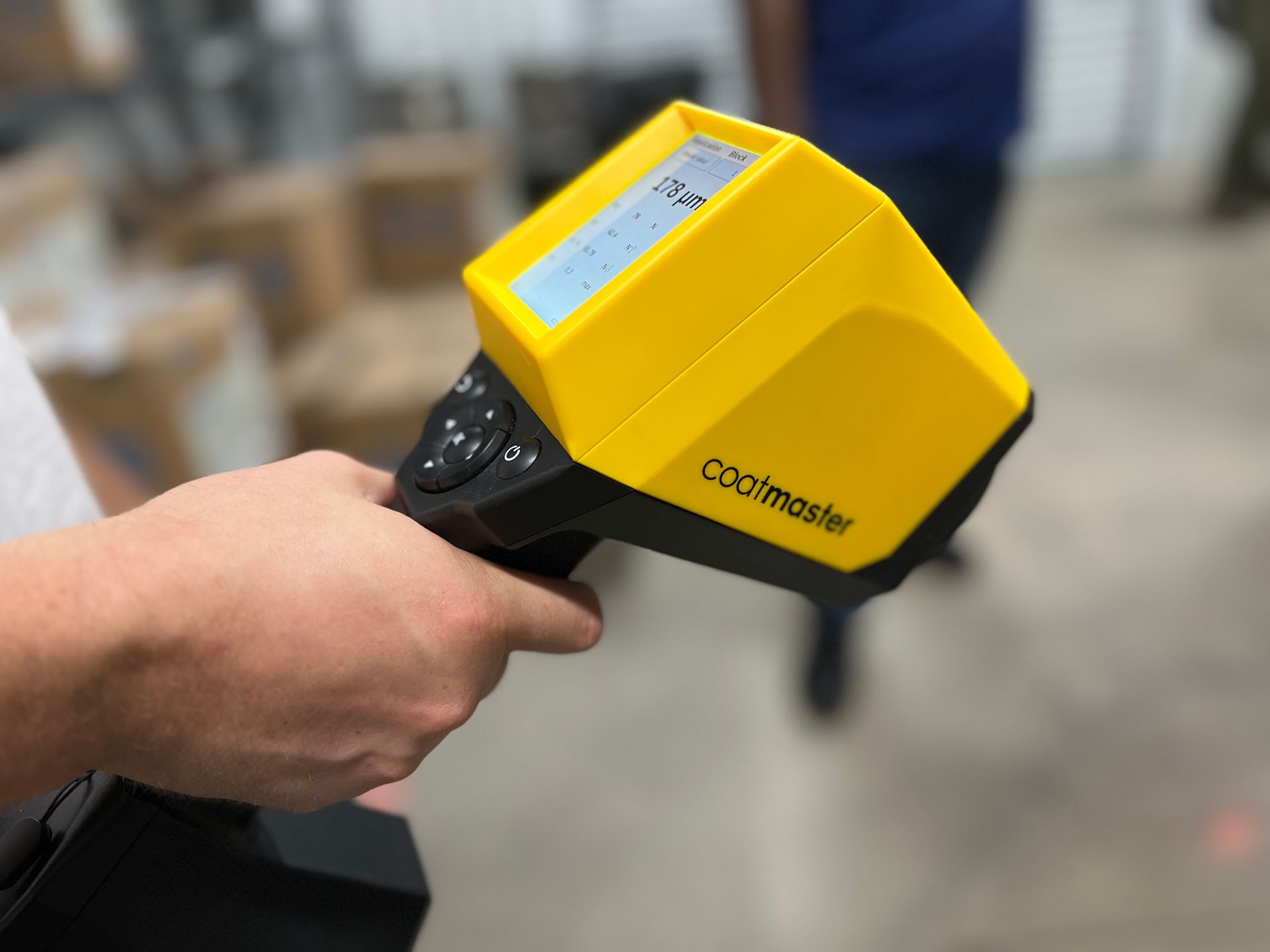 A person is holding a yellow and black device that says coomaster on it