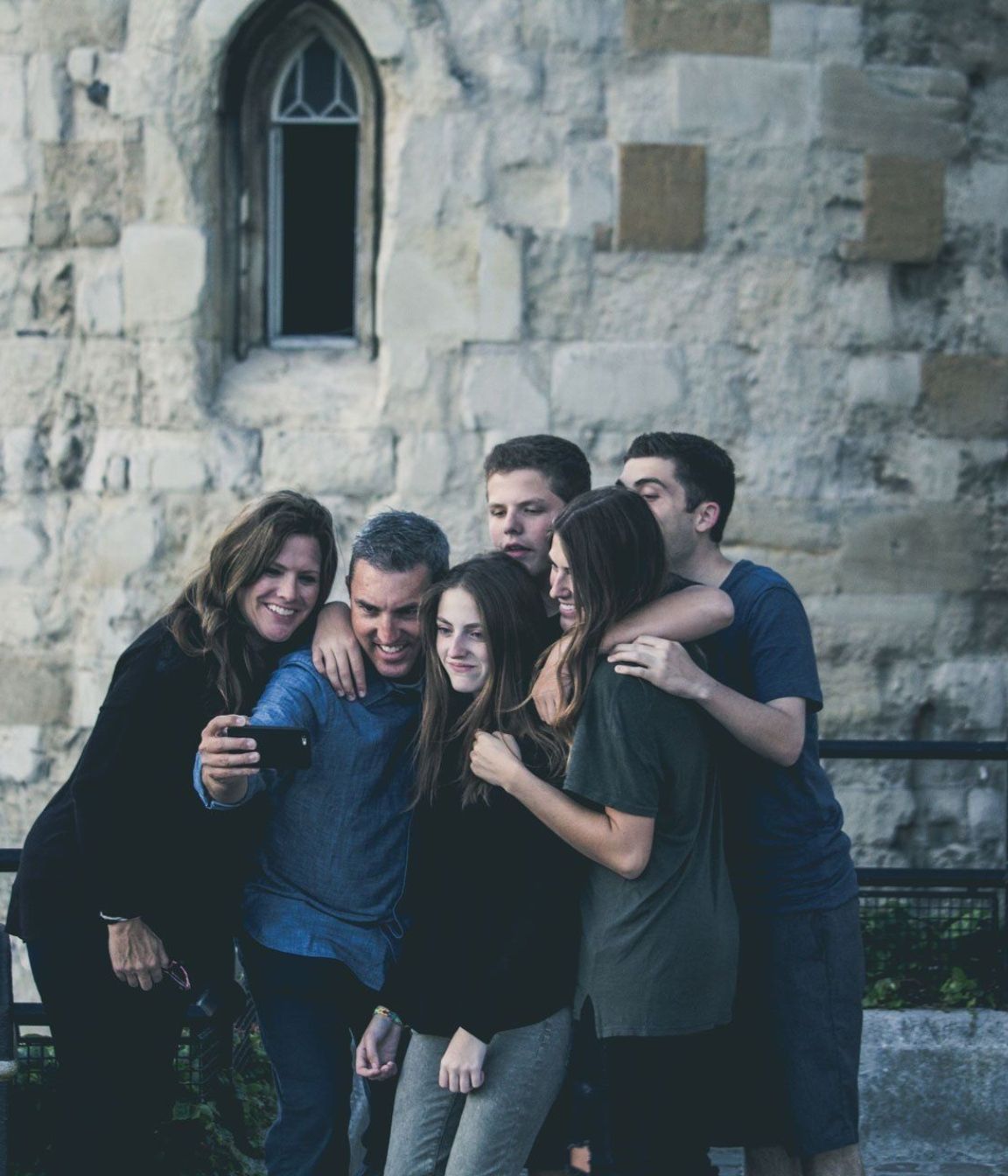 Family Therapy A family posing for a picture in front of a stone wall.