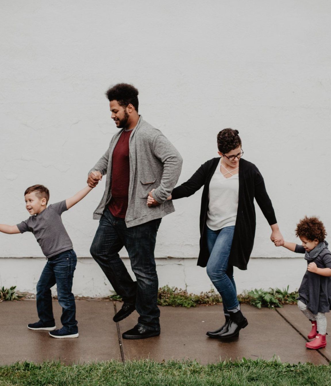 Parenting A family is walking down a sidewalk holding hands.