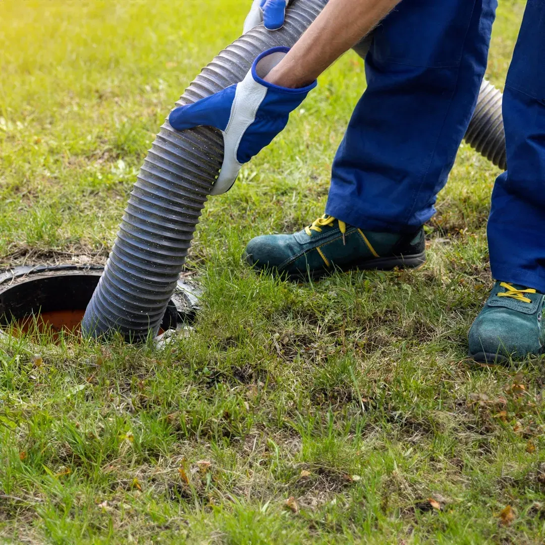 Septic technician holding a hose, performing regular maintenance and inspections for optimal septic system performance