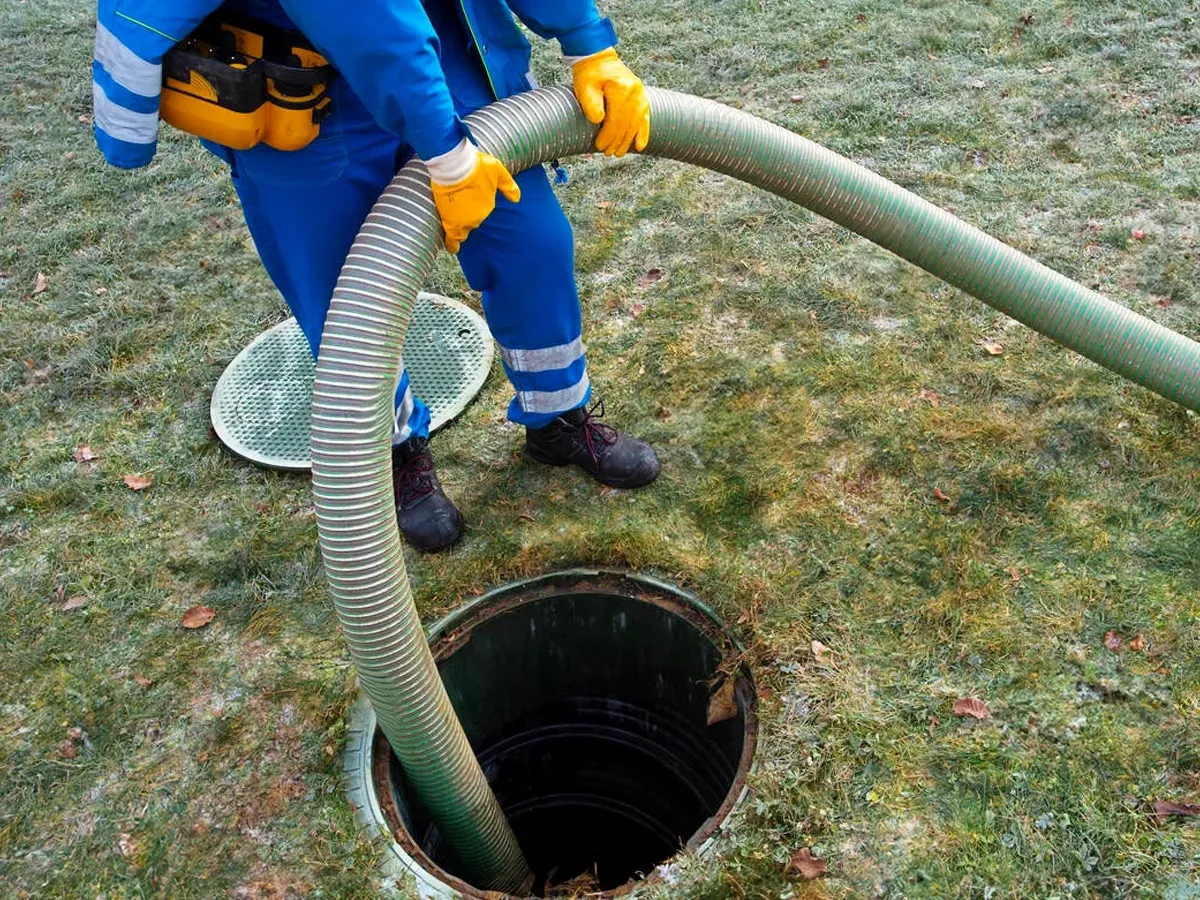 Septic technician using drain cleaning hose for maintenance and inspection